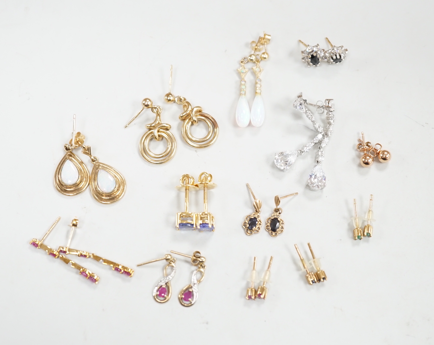 Ten assorted pairs of 9ct and 9ct and gem set earrings, including white opal, gross weight 22.3 grams, together with three other pairs of yellow metal and gem set small ear studs(lacking butterflies)